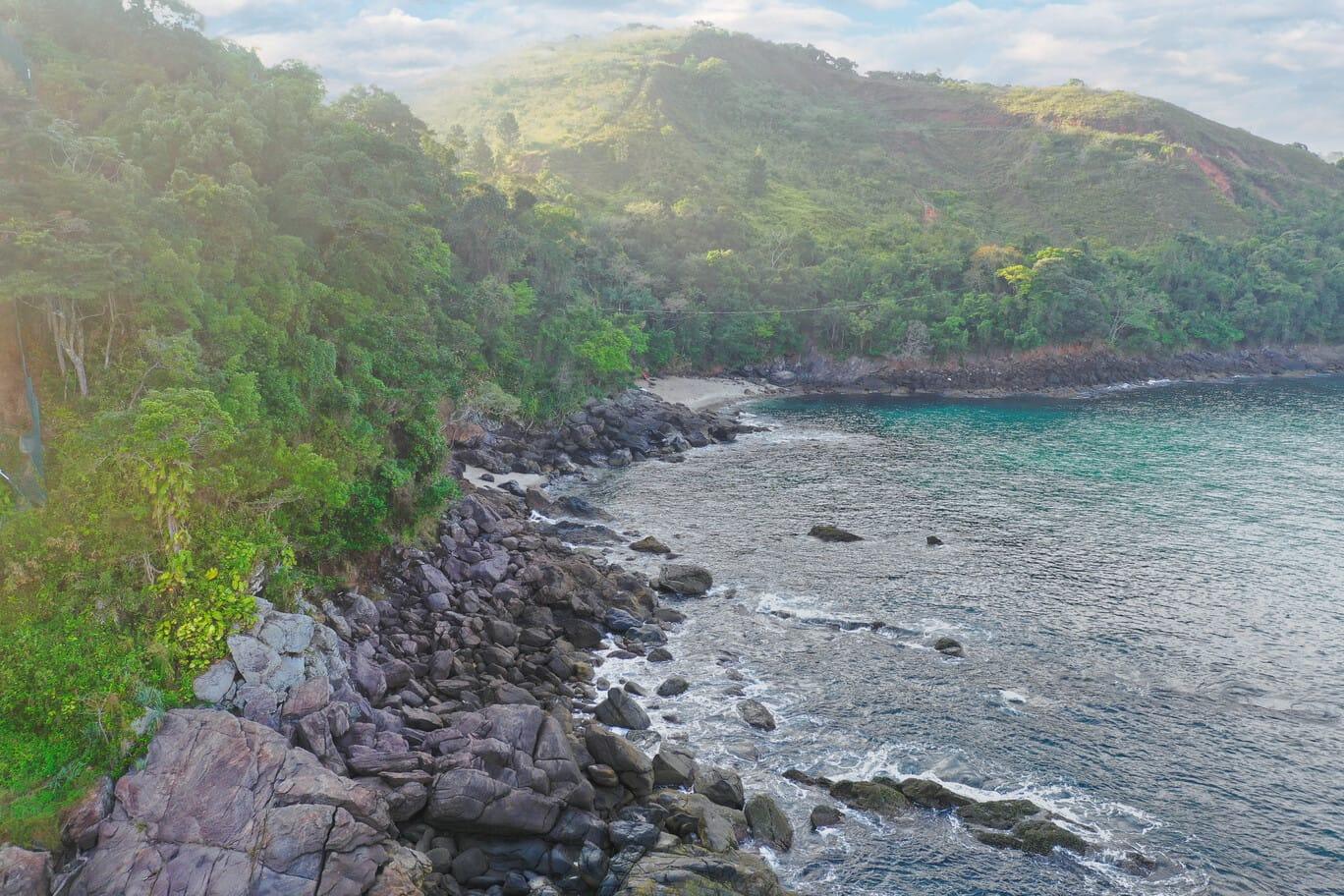 Costão rochoso coberto por vegetação junto ao mar na costa de Maresias.